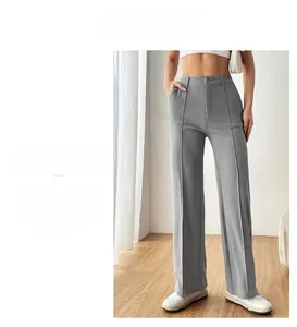 Detail of high-waisted grey trousers showing fabric drape and sharp front crease design