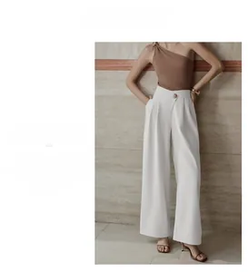 Detailed view of white high-waisted wide-leg trousers featuring a gold button decoration