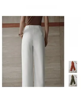 Detail of high waisted white wide leg pants featuring an elastic waistband and draped fabric