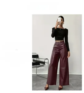 Dettaglio dei pantaloni a gamba larga in ecopelle a vita alta in un bordeaux scuro lucido