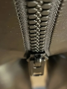 Gros plan des dents de fermeture éclair en métal argenté sur un legging en cuir PU brillant