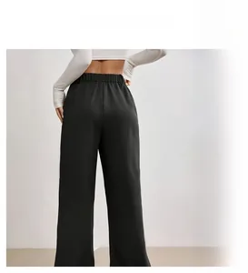 Detail of high waist black wide leg trousers with loose fit and draping fabric