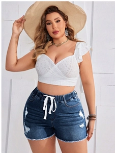 Outfit estivo con crop top in pizzo bianco e pantaloncini di jeans strappati con nappe