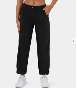 Detailopname van de zwarte corduroy broek voor dames met rechte pijpen en geplooide taille