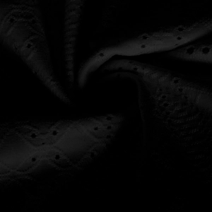 Macro shot of black broderie anglaise lace fabric with delicate embroidered hollow patterns
