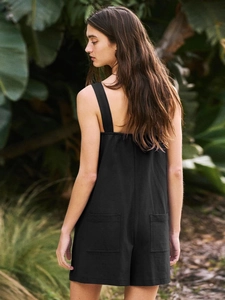 Detail view of the back of a black summer romper with two square pockets in a tropical garden