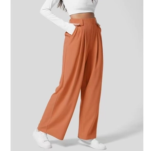 Dettaglio dei pantaloni a gamba larga a vita alta marrone-arancio con tessuto liscio di qualità