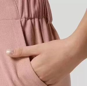 Dettaglio dei pantaloni a vita alta in tessuto a nido d'ape malva con tasche