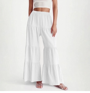 Detail view of white tiered wide-leg pants featuring vertical texture and elastic high waist