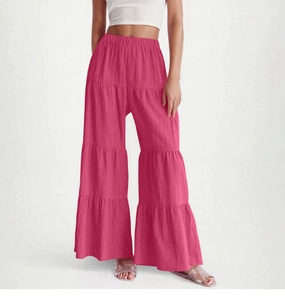 Detail of tiered wide-leg pants in rose pink featuring pleated texture and elastic waist