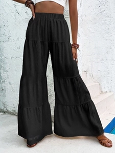 Women's black high-waisted wide-leg tiered trousers with elastic waistband and pleats