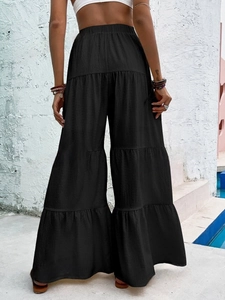 Women's black high-waisted tiered wide-leg trousers with elastic waist and bohemian style