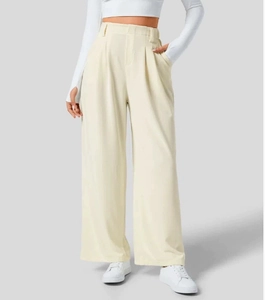 Dettaglio dei pantaloni a vita alta color crema a gamba larga con pieghe e tasche laterali