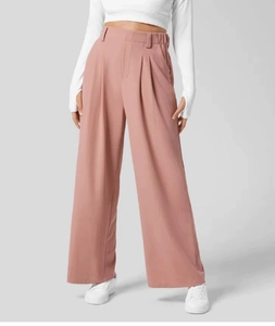 Dettaglio dei pantaloni a gamba larga a vita alta drappeggiati in rosa antico con pieghe
