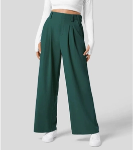 Dettaglio dei pantaloni a gamba larga verde scuro a vita alta con drappeggio e pieghe