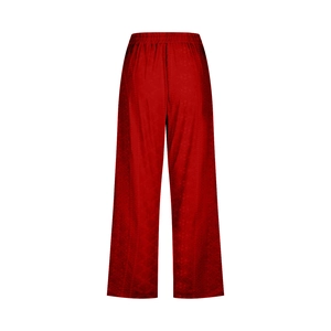 Detail of red wide-leg trousers showing elastic high waist and dark geometric prints