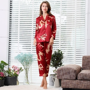 Red silk satin couples pajama set with gold dragon print in a bright home setting