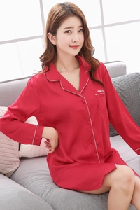 Close-up of red silk pajamas featuring white piping trim and embroidered chest pocket
