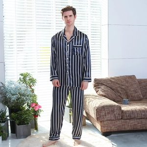 Men's navy blue striped silk-like pajama set with long sleeves in a cozy home setting