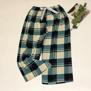 Close-up of green plaid pajama pants with elastic waistband and white satin bow detail