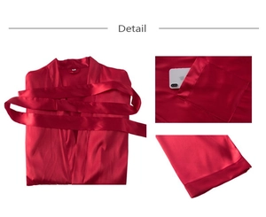 Détail d'un peignoir en satin rouge montrant la texture soyeuse, la ceinture et la poche