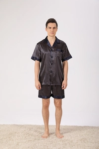 Détail d'un pyjama en satin bleu marine à rayures dorées avec col à revers et poche poitrine