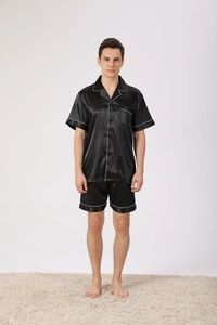 Men's black satin pajama set detail showing silky fabric texture and white contrast piping