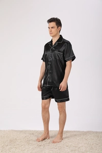 Detail of men's black satin pajama set showing contrast white piping and silk texture