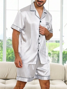 Detail of silver grey men's satin pajama set with black trim and glossy silk texture