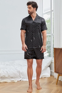Détail du tissu de pyjama en satin noir montrant l'éclat de la soie et les pois blancs