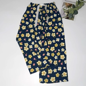 Detail of floral sleep trousers featuring white satin ribbon and dark blue cotton fabric