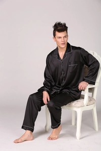 Detail of men's black satin pajamas with long sleeves and white contrast piping trim