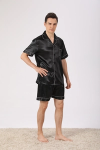 Detail of men's black satin pajama set with contrast white piping and a chest pocket