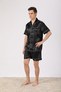 Detailed view of men's black silk pajamas set with white piping and button-down collar