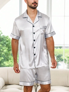 Detail of silver silk satin men pajamas set featuring black contrast piping and chest pocket