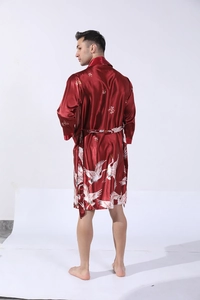 Detail of men's dark red satin robe showing white crane patterns and fabric texture