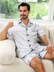 Men's loose silver ice silk pajama set with short sleeves and shorts on a light sofa