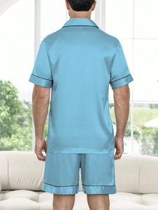Rear view of light blue satin pajamas with black piping in a bright interior setting