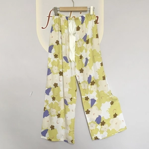 Detail of floral printed pajama pants featuring yellow rayon fabric and ribbon tie