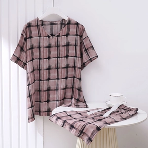 Detail view of pink plaid cotton pajamas with white drawstring on a white table