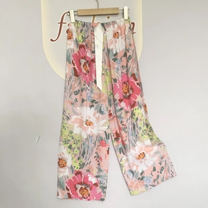 Detail of floral pajama pants featuring a wide white satin ribbon tie on the waist