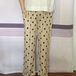 Detail of loose fit polka dot wide leg pants featuring side pockets and elastic waist