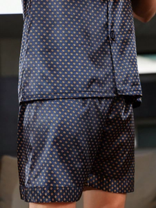 Gros plan du tissu satiné du pyjama avec motifs géométriques bleu foncé et orange