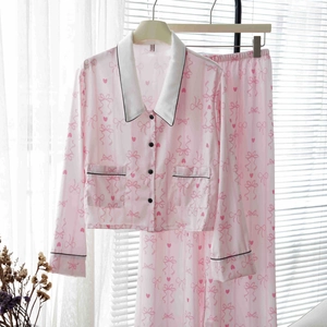 Pink striped silk pajama set with long sleeves and bow pattern on a white hanger