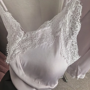 Vue détaillée de la nuisette en satin blanc avec dentelle de cils délicate et décolleté en V