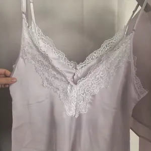 Détail du caraco en satin avec bordure en dentelle florale et décolleté en V soyeux
