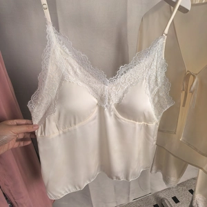 Détail d'un caraco en satin de soie blanc avec bordure en dentelle cil et fines bretelles
