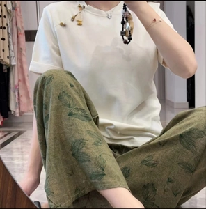 Detail of white cotton T-shirt with leaf print wide-leg trousers in a relaxed style