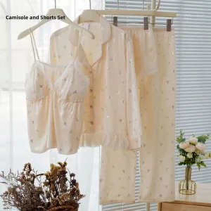 Dettaglio canotta in seta beige con bordo in pizzo bianco e stampe a fiocco argentato