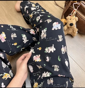 Detail view of cotton pajama pants with cute cartoon dog patterns on black fabric